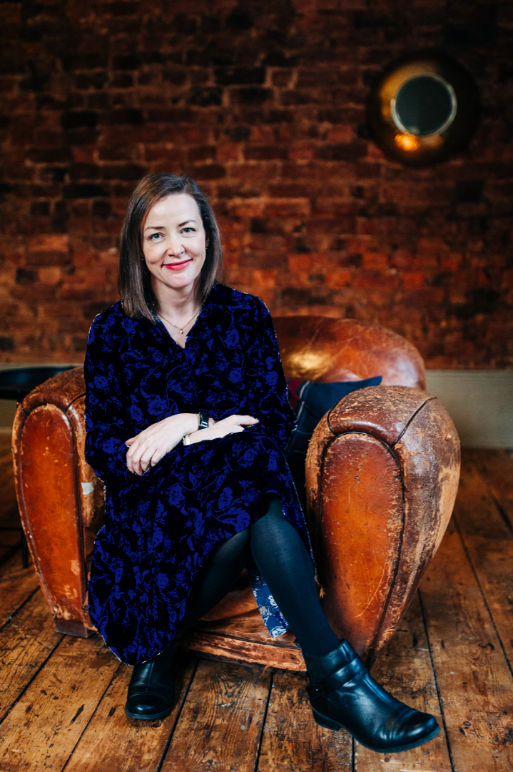 Maria McHale smiling sitting on a chair